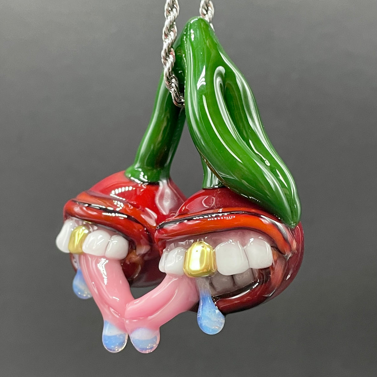 Cherry Lover handblown glass pendant - paired red cherries with green stem, each with open grinning mouth, white teeth, gold tooth, pink tongues, silver rope chain - Leviathan Glass