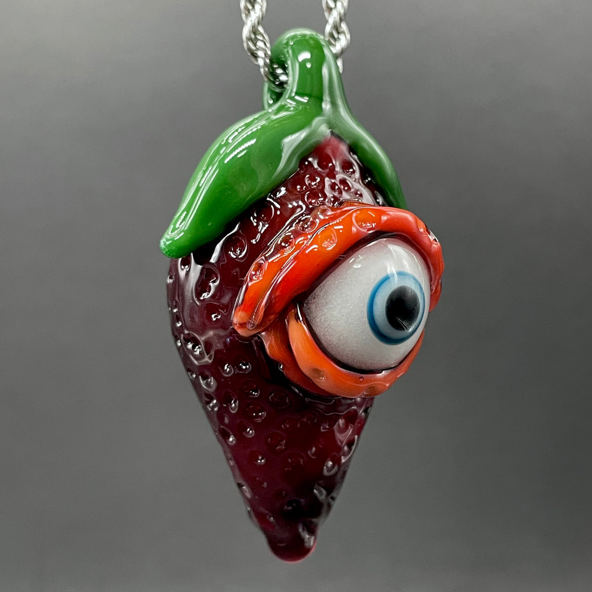 Close-up of Cyclops strawberry pendant - handcrafted glass