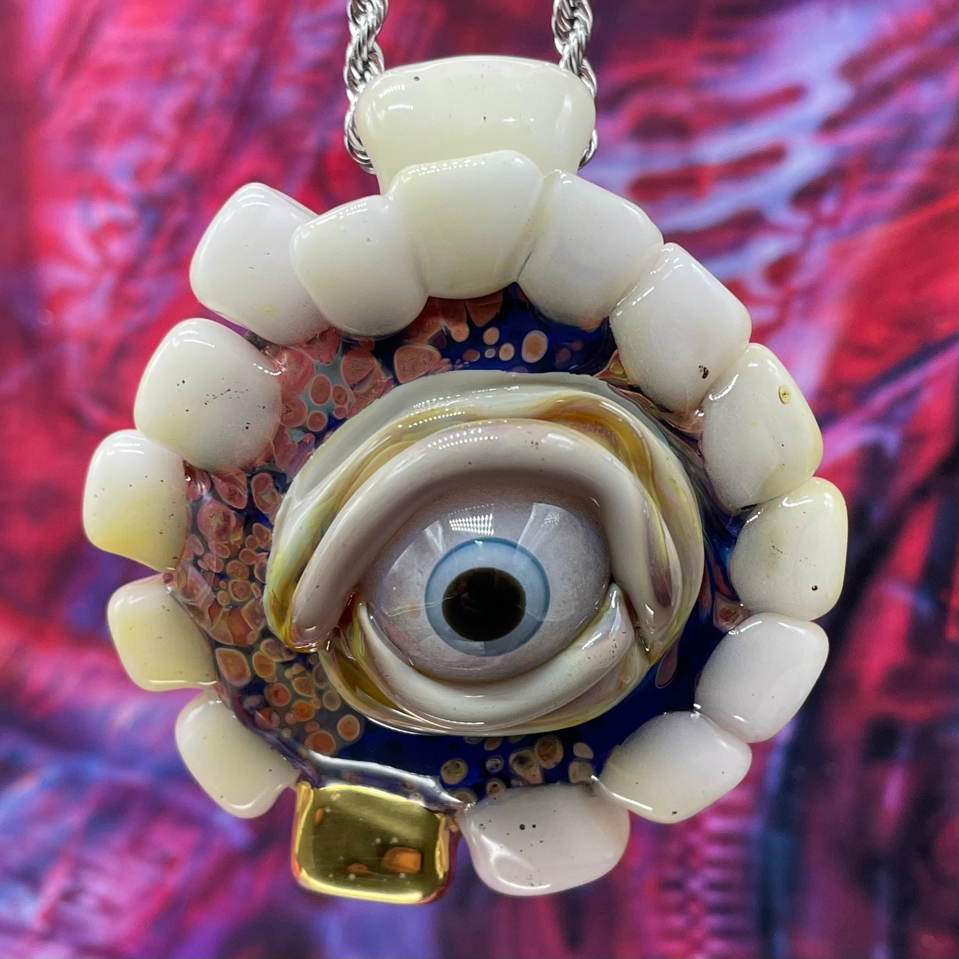 Unidentified Object Delta handblown glass pendant - circular disc ringed with ivory teeth, blue iris eye center, eyelid, gold tooth accent, silver rope chain - Leviathan Glass