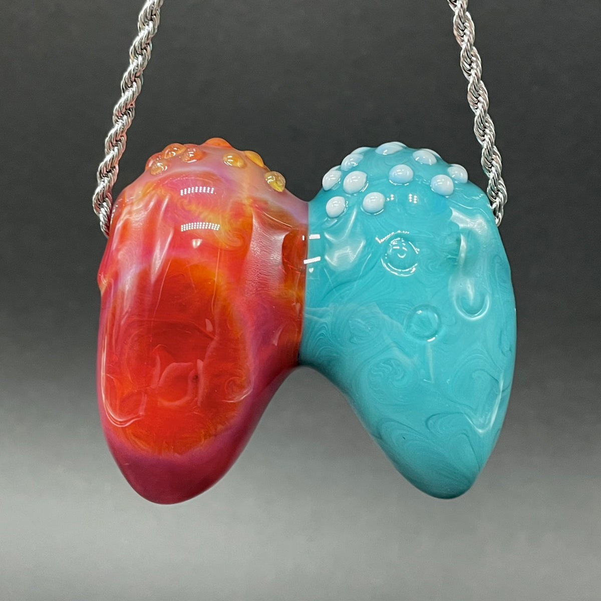 Two Headaches Are Better Than One handblown glass pendant - teal cyclops head with white teeth and green slime fused with red cyclops head with pink tongue, silver rope chain - Leviathan Glass