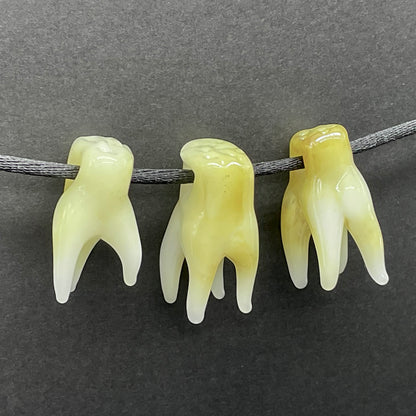 Close-up of 3 glass tooth beads - handcrafted glass