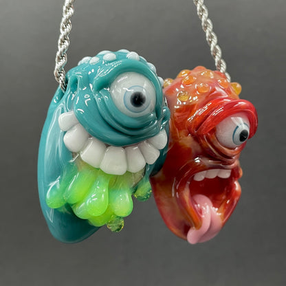 Two Headaches Are Better Than One handblown glass pendant - teal cyclops head with white teeth and green slime fused with red cyclops head with pink tongue, silver rope chain - Leviathan Glass