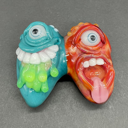 Two Headaches Are Better Than One handblown glass pendant - teal cyclops head with white teeth and green slime fused with red cyclops head with pink tongue, silver rope chain - Leviathan Glass