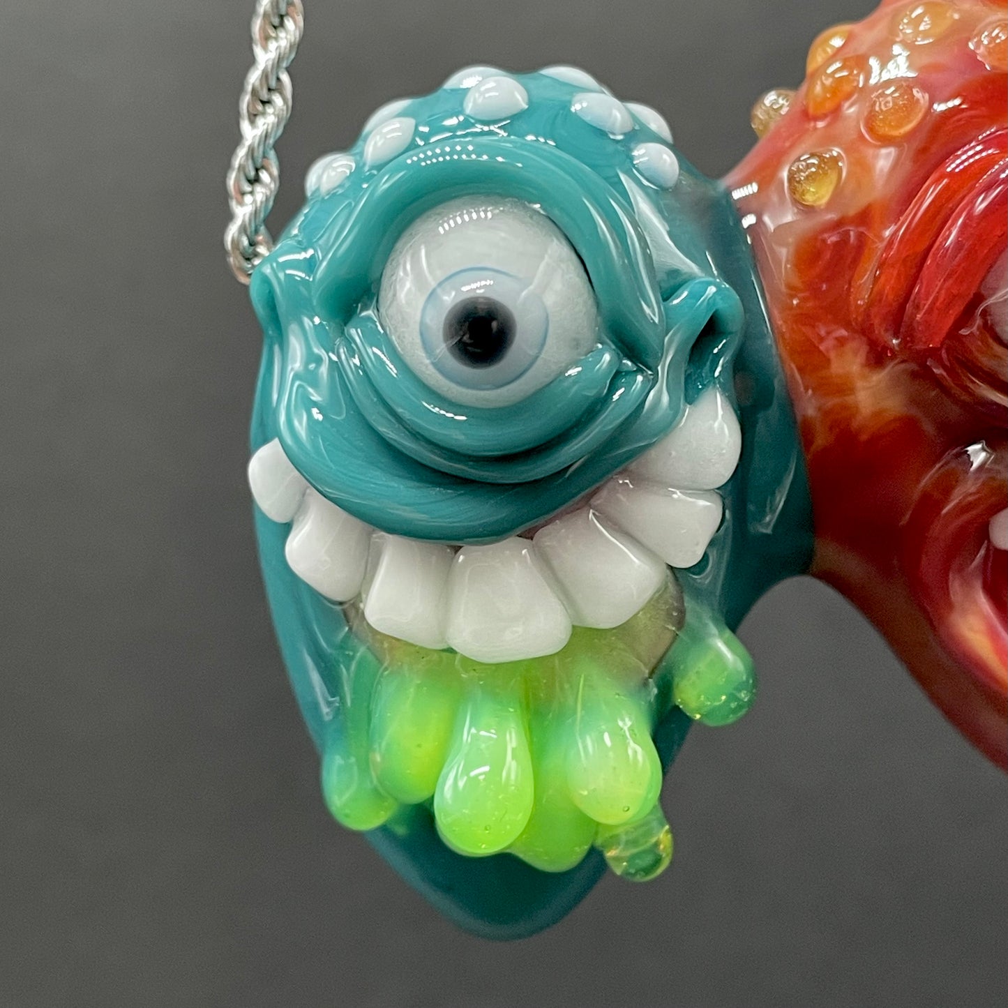 Two Headaches Are Better Than One handblown glass pendant - teal cyclops head with white teeth and green slime fused with red cyclops head with pink tongue, silver rope chain - Leviathan Glass