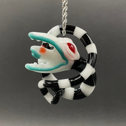 Beetlejuice Inspired handblown solid glass Sandworm sculpture - coiled black and white striped sandworm with white worm head, teal tongue, red eyes - Leviathan Glass

Beetlejuice sand worm hand blown glass pendant. contains black and white striped, twisting snake body. a large monster head with red eyes eating a smaller snake head in its mouth. 