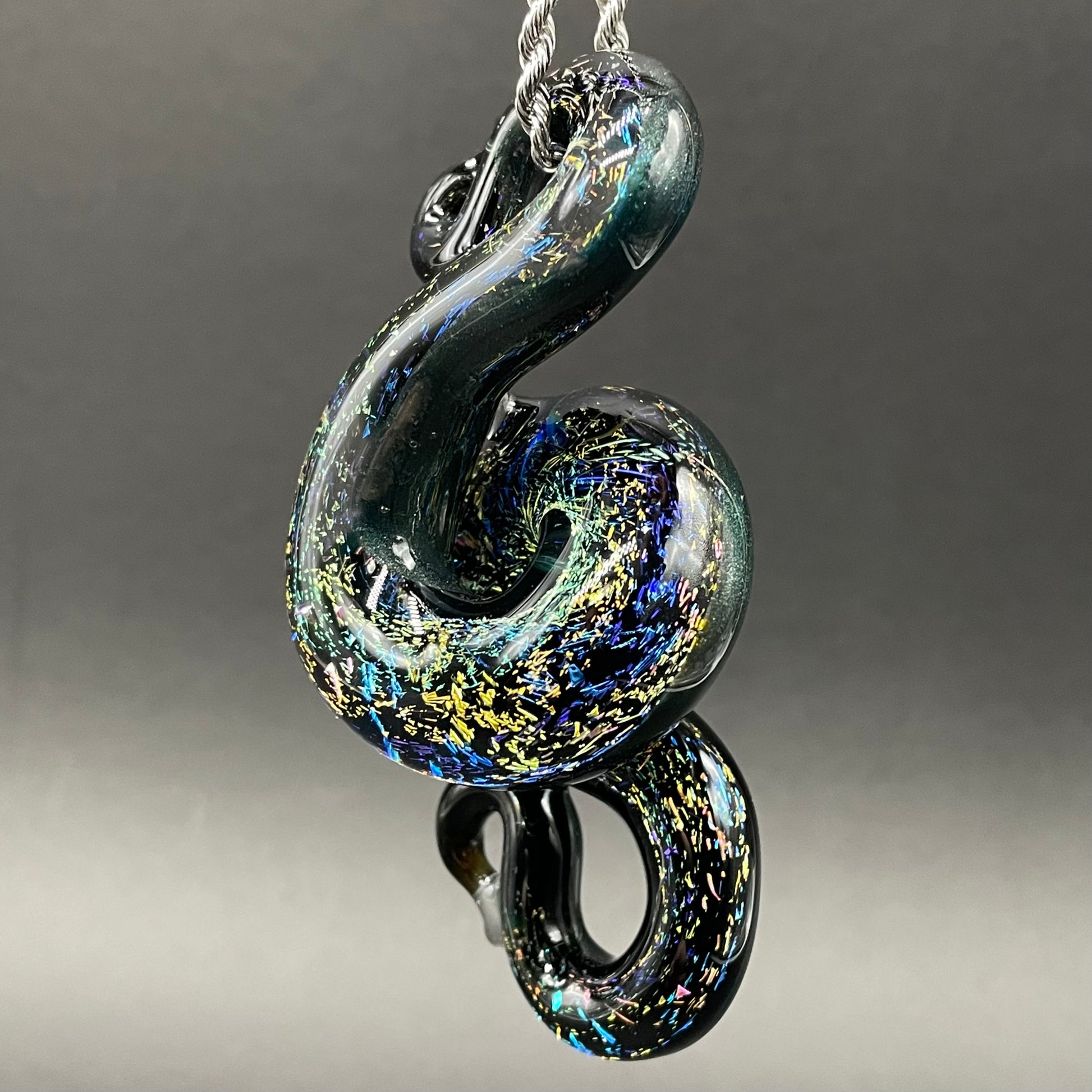 Close-up of Dichroic rainbow sparkle snake pendant - handcrafted glass