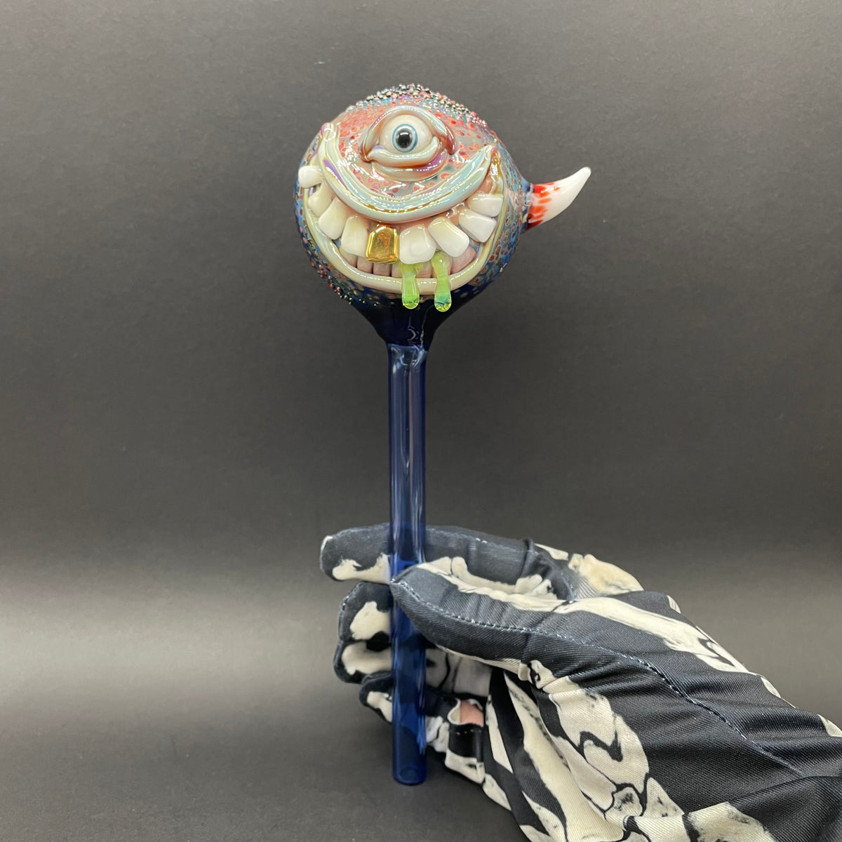 Hand Blown Glass Monster Watering Globe - round cyclops head, blue iris eye, white teeth, gold tooth, teal tongue drips, teal glass stake - Leviathan Glass
