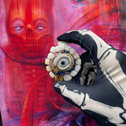 Unidentified Object Delta handblown glass pendant - circular disc ringed with ivory teeth, blue iris eye center, eyelid, gold tooth accent, silver rope chain - Leviathan Glass