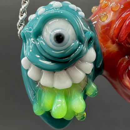 Two Headaches Are Better Than One handblown glass pendant - teal cyclops head with white teeth and green slime fused with red cyclops head with pink tongue, silver rope chain - Leviathan Glass