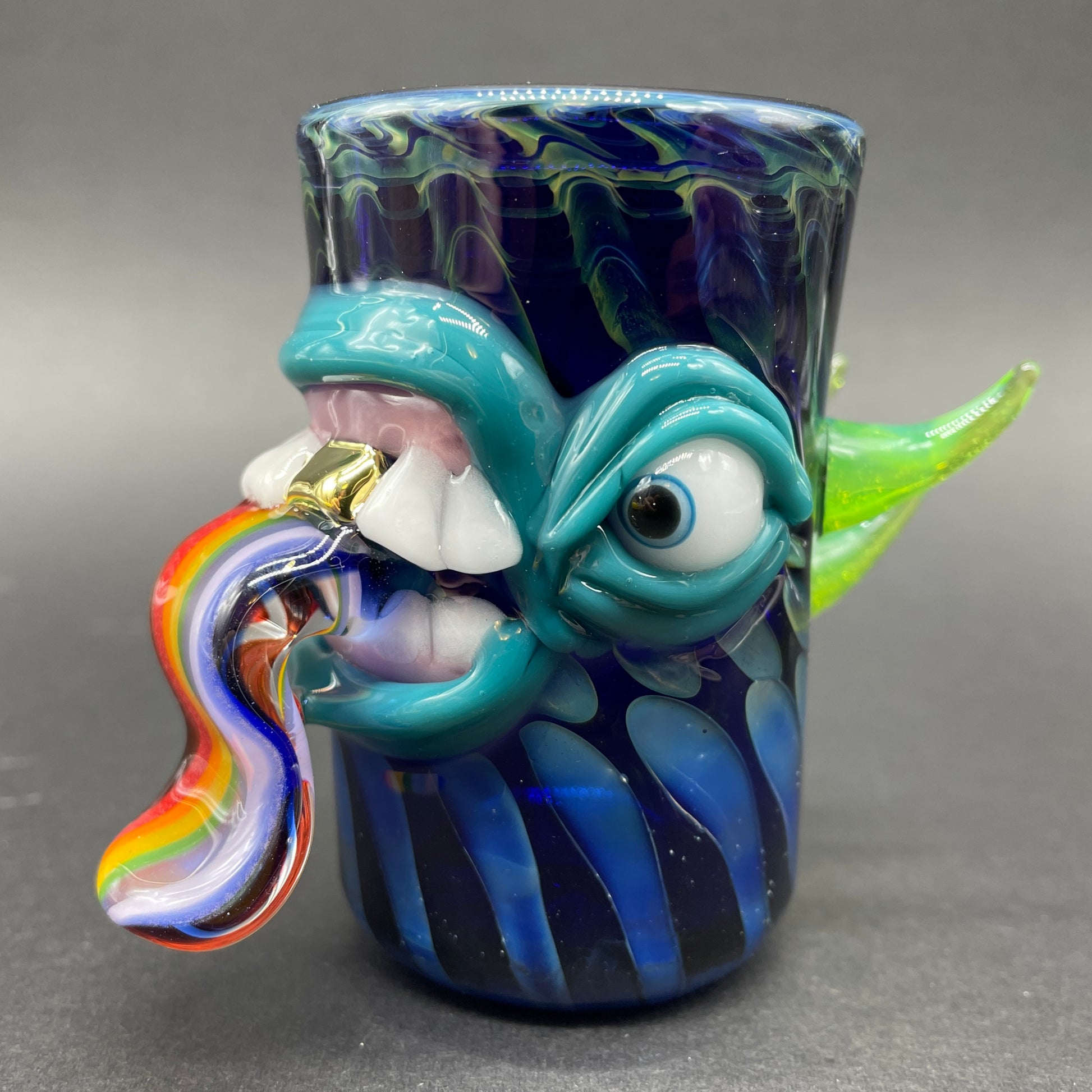 Close-up of Hand blown kool AID tongue shot glass with gold tooth - handcrafted glass