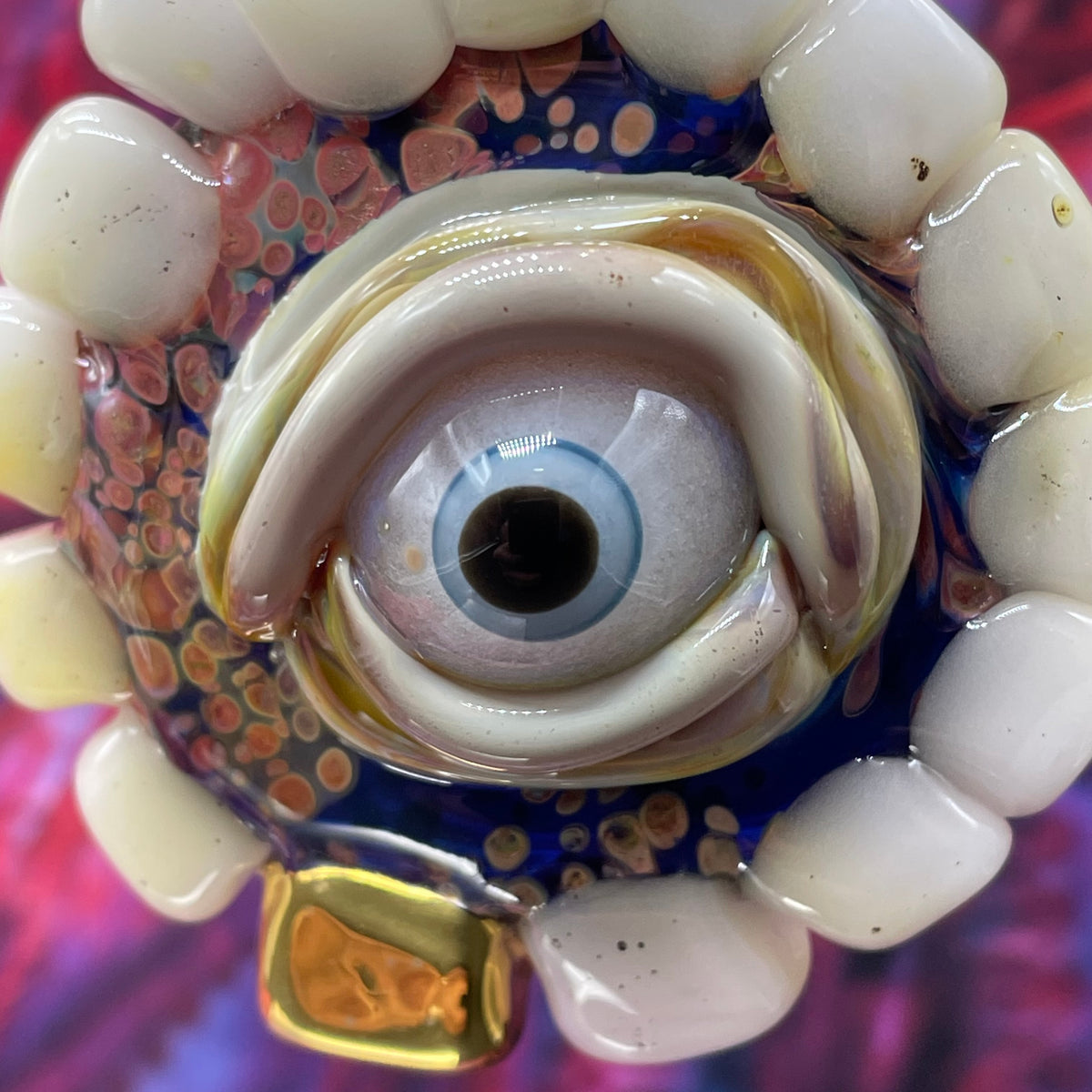 Unidentified Object Delta handblown glass pendant - circular disc ringed with ivory teeth, blue iris eye center, eyelid, gold tooth accent, silver rope chain - Leviathan Glass