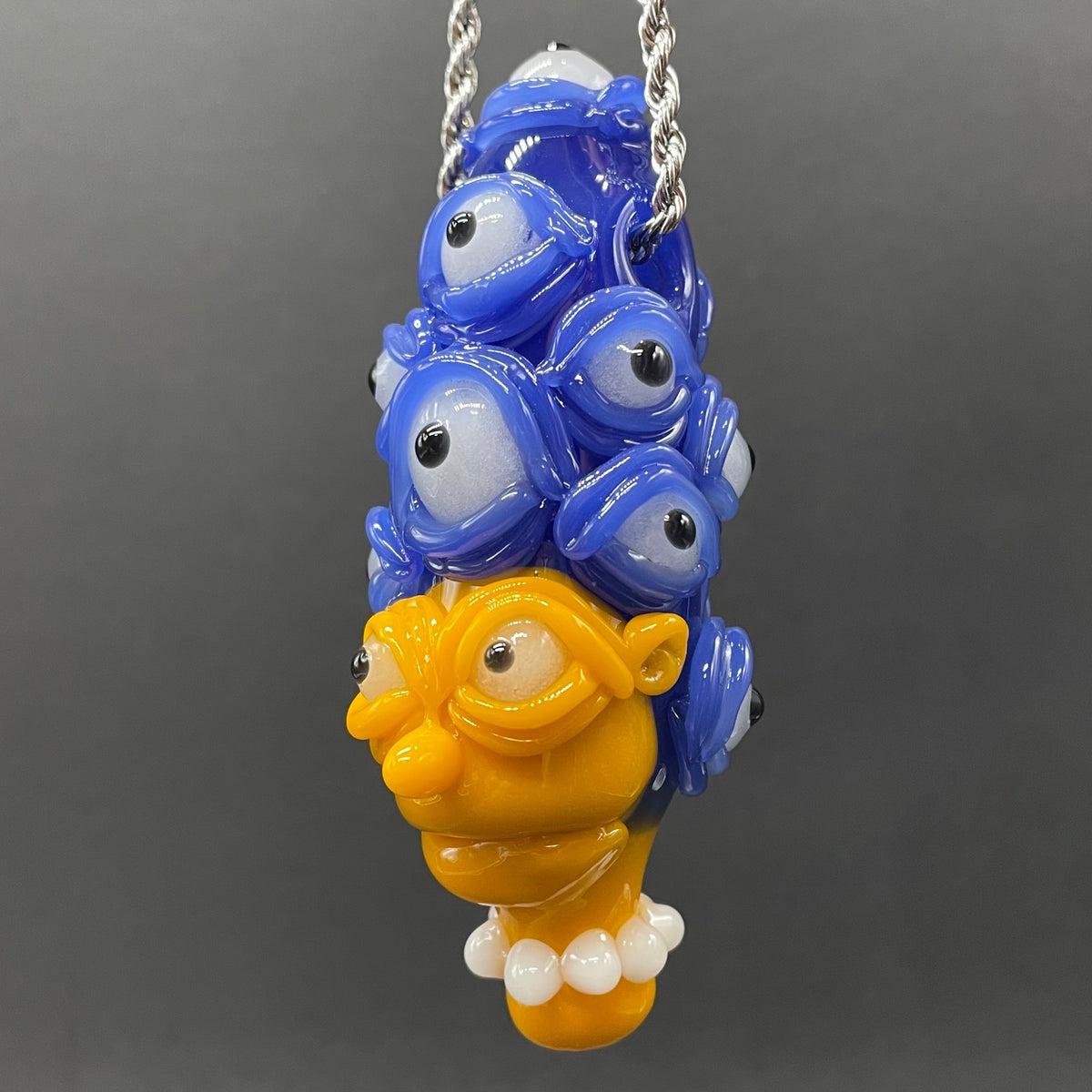 Marge Simpson Mutant handblown glass pendant - yellow Marge Simpson face with towering stack of blue cyclops creatures forming her hair, white pearl beads, silver rope chain - Leviathan Glass