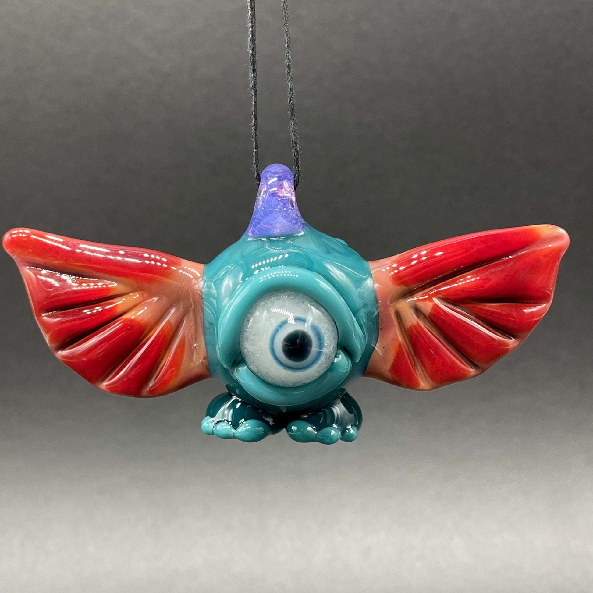 Close-up of flying cyclops pendant - handcrafted glass