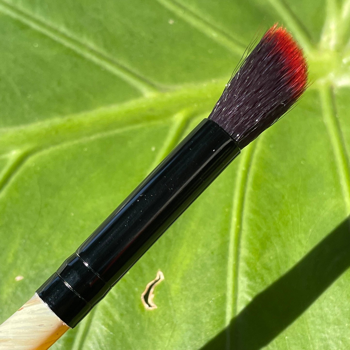 Close-up of Glass makeup brush with glow in the dark eye and carved ventral scales. - handcrafted glass